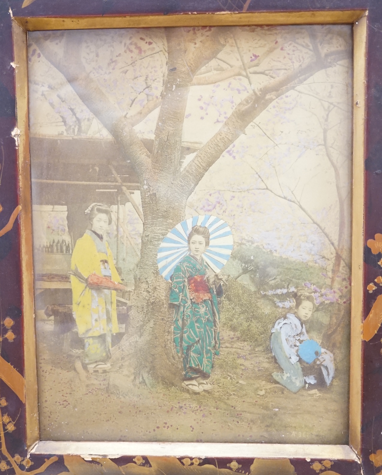 A pair of Japanese lacquered frames housing hand coloured photographs of women wearing kimonos, overall 37 x 31cm. Condition - poor